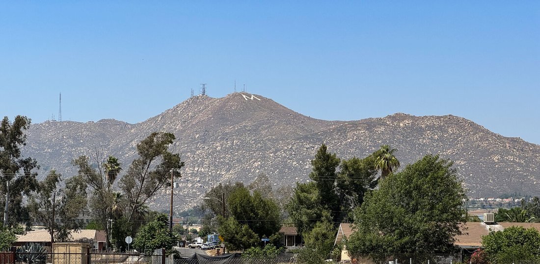 A tall mountain with a lone white M on the slope above the Moreno Valley neighborhoods